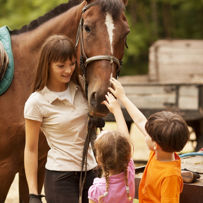Equine instructor teaching two children about horses.